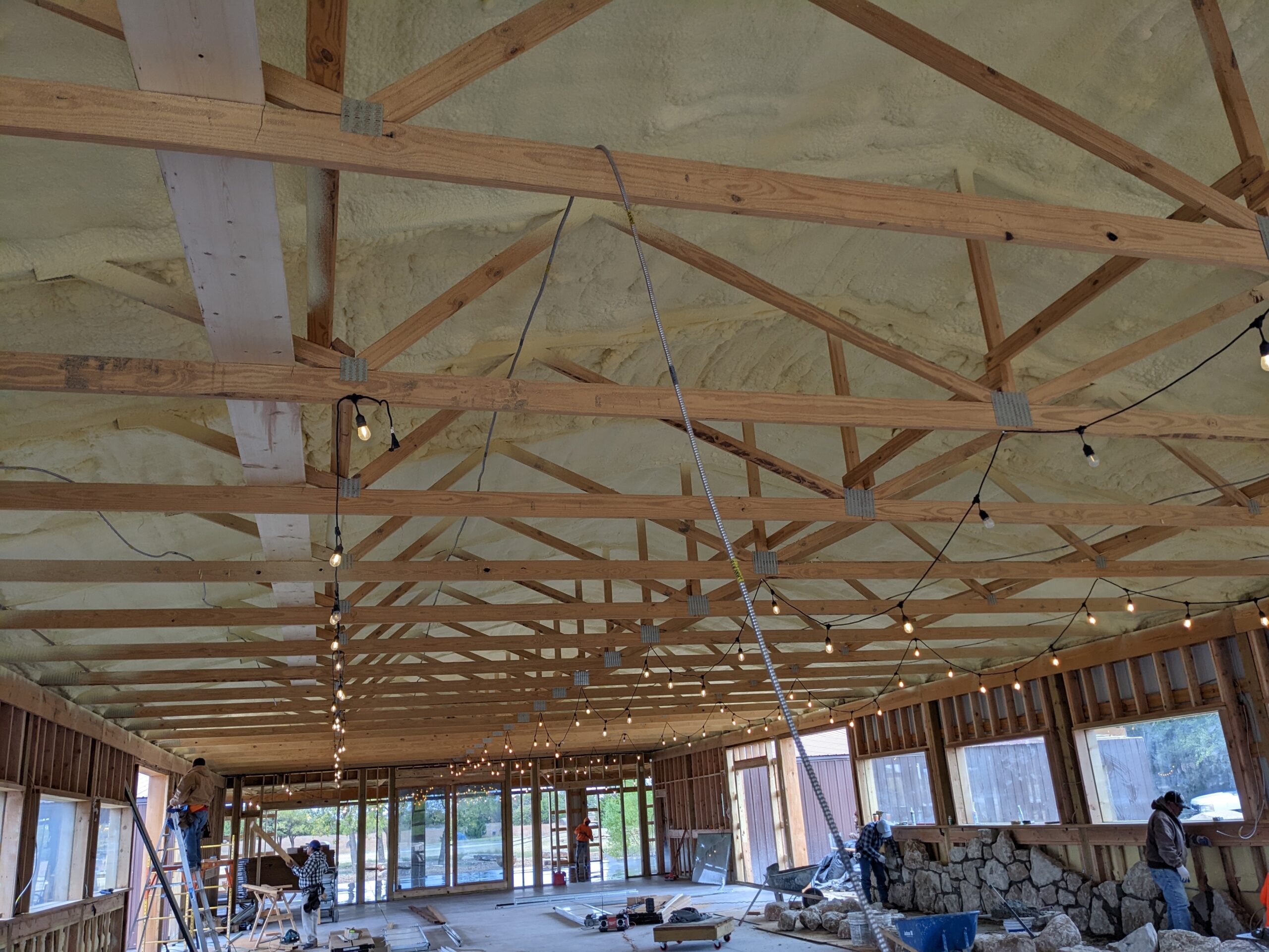 Spray foam insulated ceiling with exposed wood trusses in new barndominium