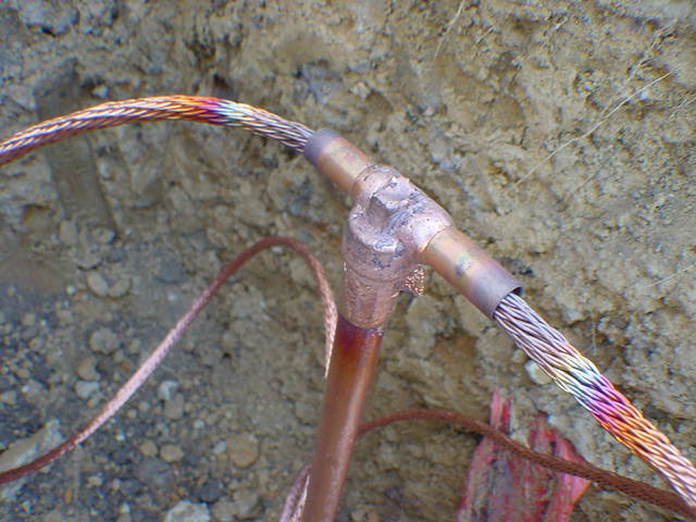 Completed exothermic cadweld weld joining three copper conductors showing mushroom-shaped solidified copper