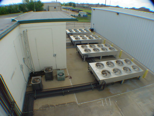 Aerial view of data center outdoor condenser array with three large multi-fan banks and refrigerant piping