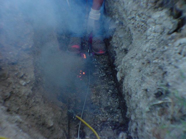 Exothermic cadweld weld firing with thermite reaction smoke joining copper conductors in grounding trench