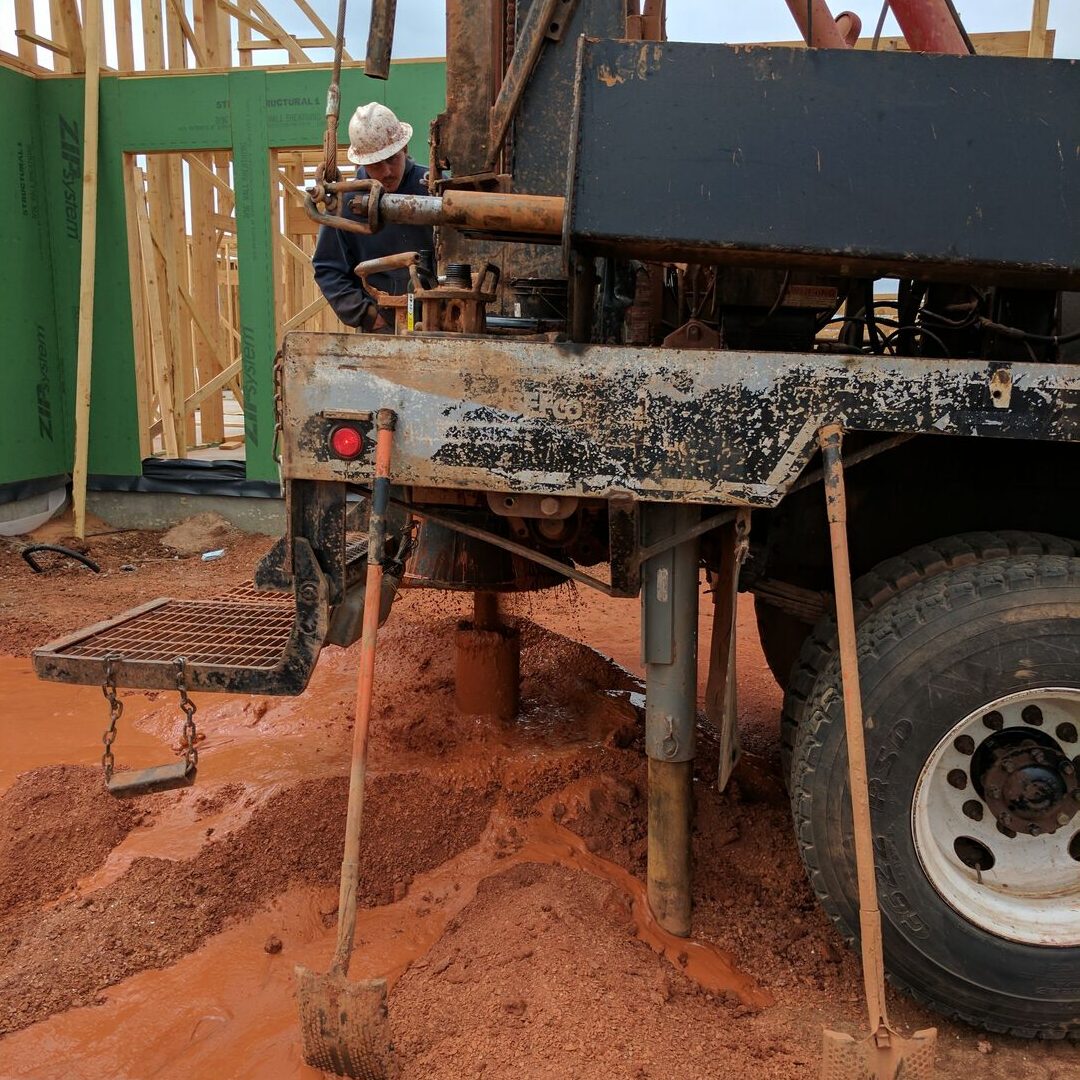 Geothermal ground loop drill rig boring vertical well into Oklahoma red clay