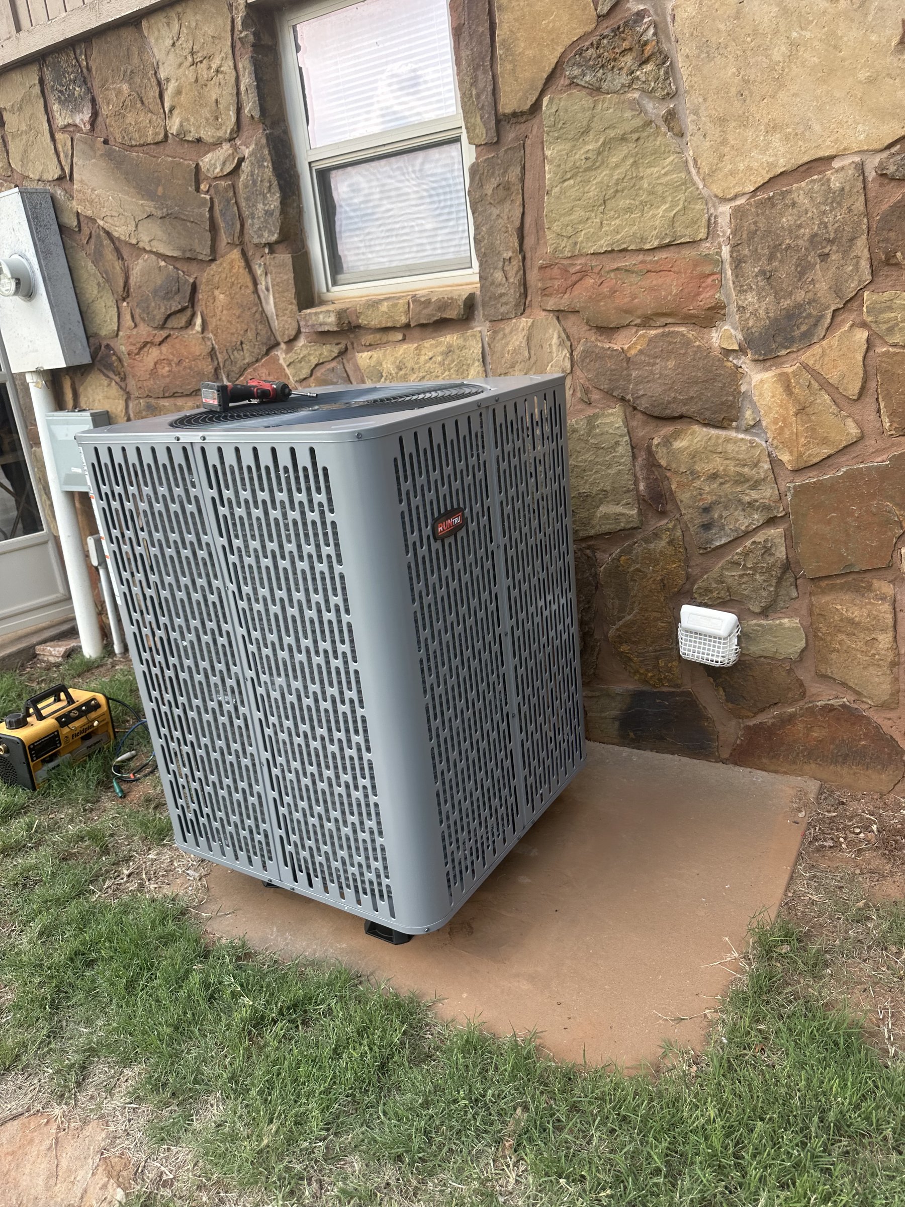 RunTru by Trane air conditioner condenser installed on pad at a stone-exterior home in central Oklahoma