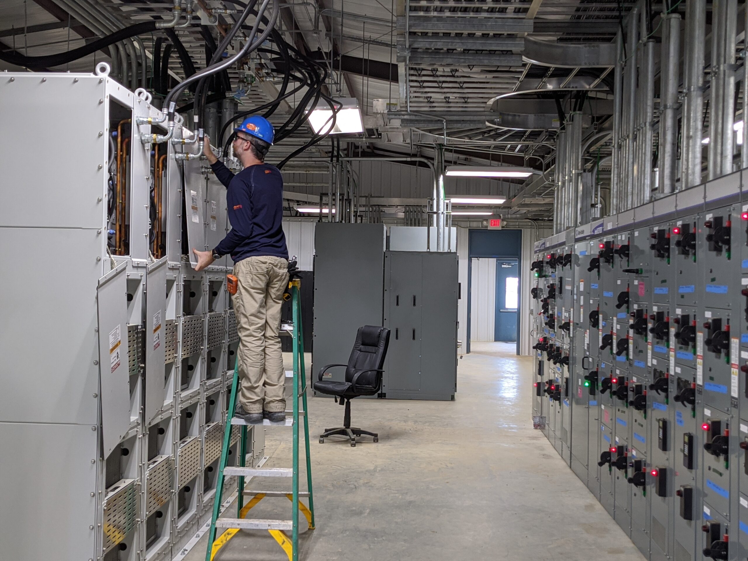Hartzell's technician in hard hat servicing liquid refrigerant cooling in industrial motor control room