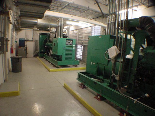 Multiple Cummins generator sets on yellow containment pads in commercial data center generator room with maintenance clipboard