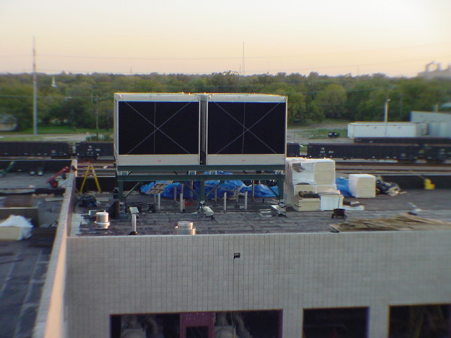 Two large cooling towers being installed on rooftop at golden hour during Sprint infrastructure project