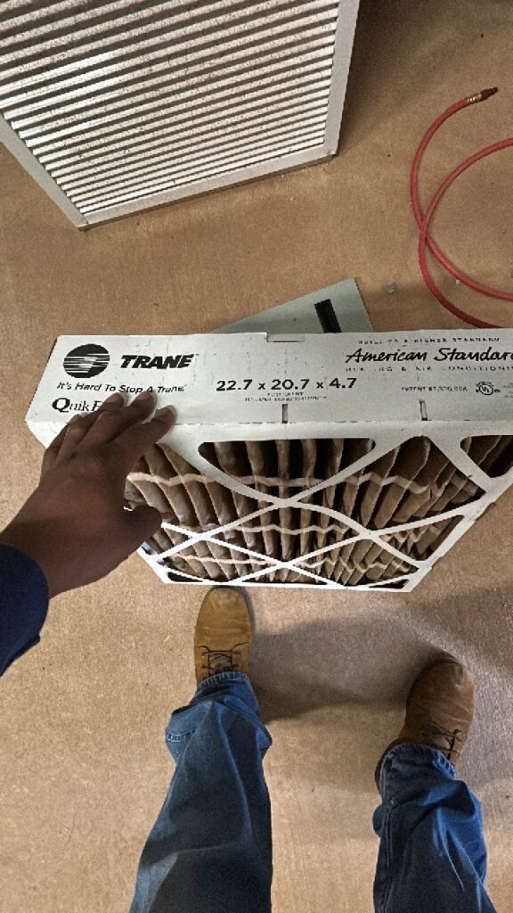 Technician holding a clogged Trane air filter pulled during an HVAC service call