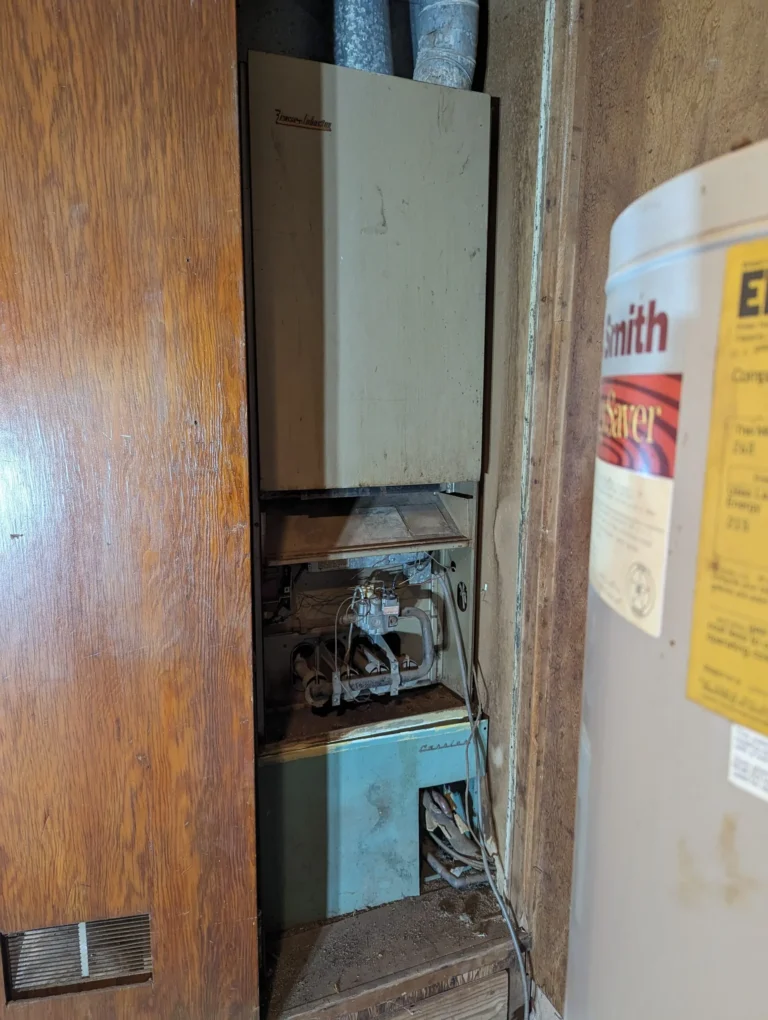 Old Carrier furnace in a cramped utility closet before replacement