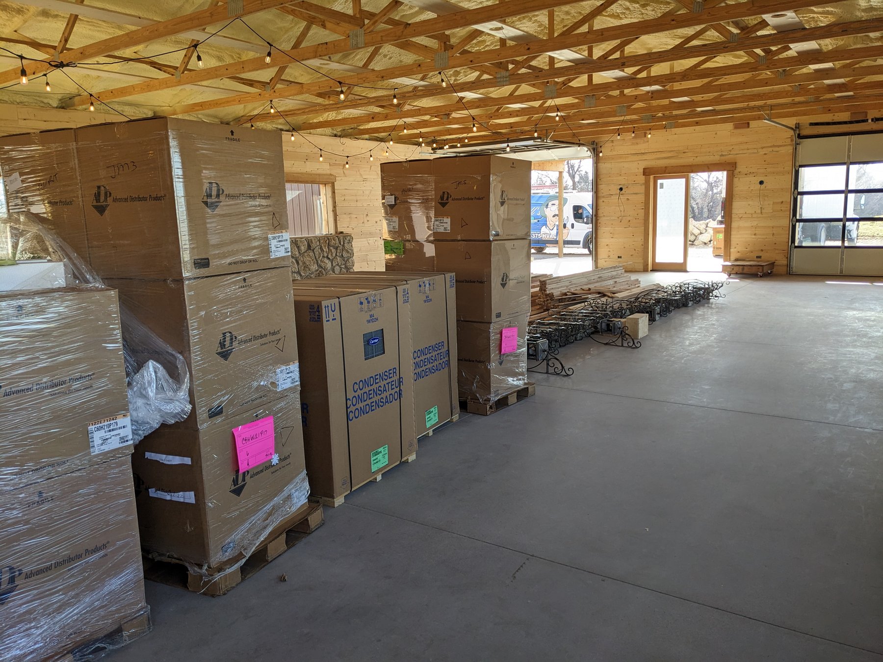 Carrier HVAC equipment staged on pallets inside the open main hall at The Cedar Gate event venue near Loyal, Oklahoma, with exposed wood trusses overhead, during a Hartzell's Heat and Air commercial install
