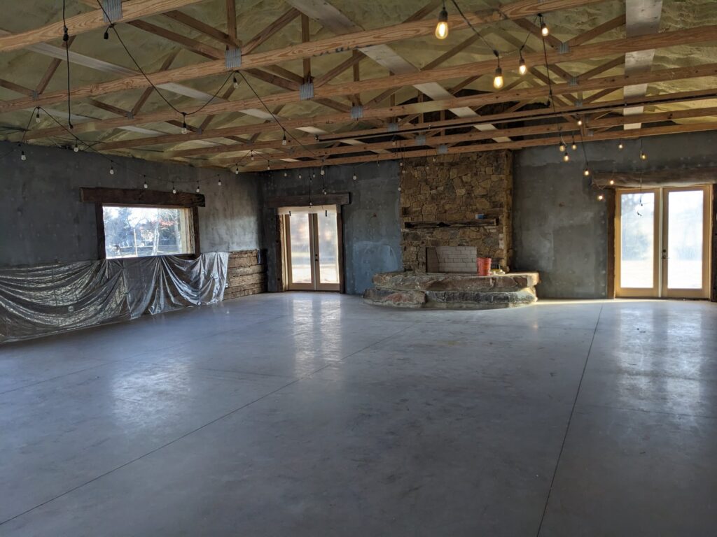 The main event hall at The Cedar Gate venue near Loyal, Oklahoma with a stone fireplace and open floor before the new commercial HVAC system went in, serviced by Hartzell's Heat and Air