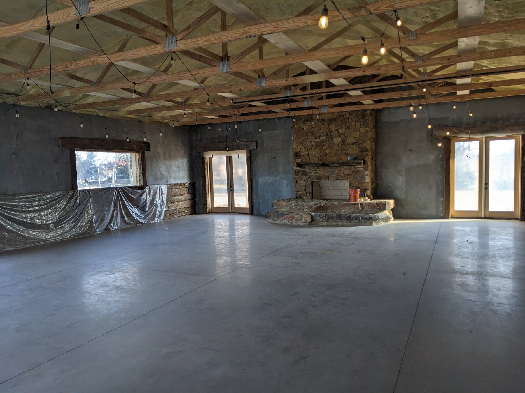 The main event hall at The Cedar Gate venue near Loyal, Oklahoma with a stone fireplace and open floor before the new commercial HVAC system went in, serviced by Hartzell's Heat and Air