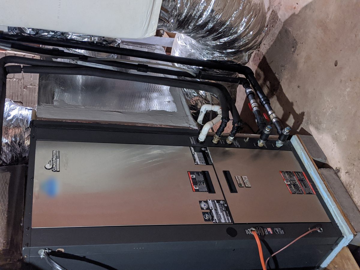 ClimateMaster Tranquility geothermal heat pump installed by Hartzell in northwest Oklahoma, with water-source loop piping and brass fittings