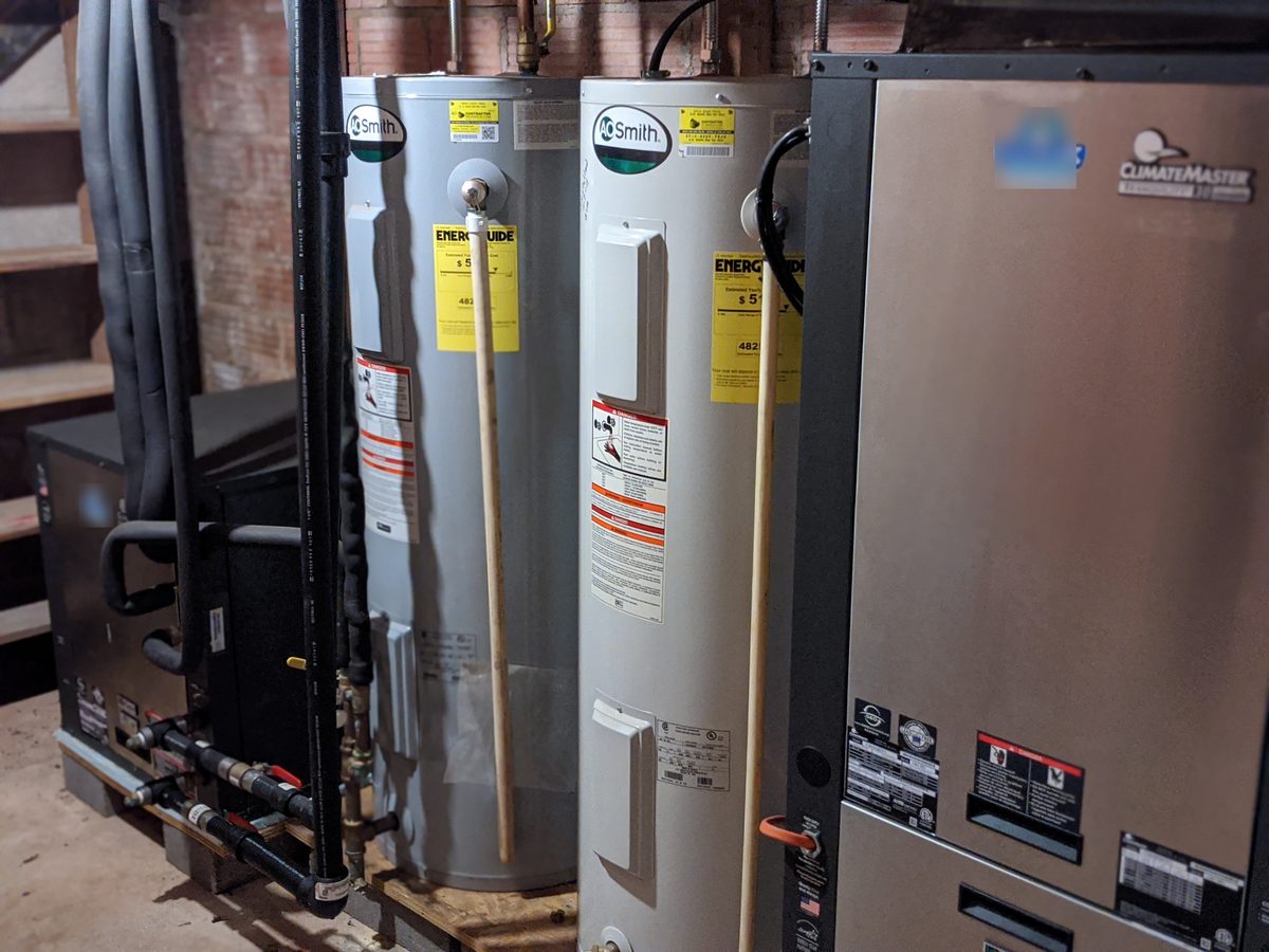 Geothermal mechanical room in northwest Oklahoma: ClimateMaster Tranquility geo units, loop manifold, and two electric water heaters for hot water generation