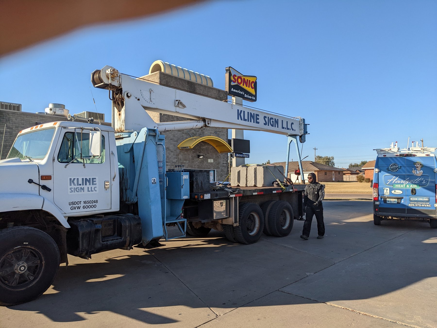 Sonic Drive-In sign with the Hartzell's Heat & Air van and a crane truck on site during a commercial rooftop unit replacement in Kingfisher, Oklahoma