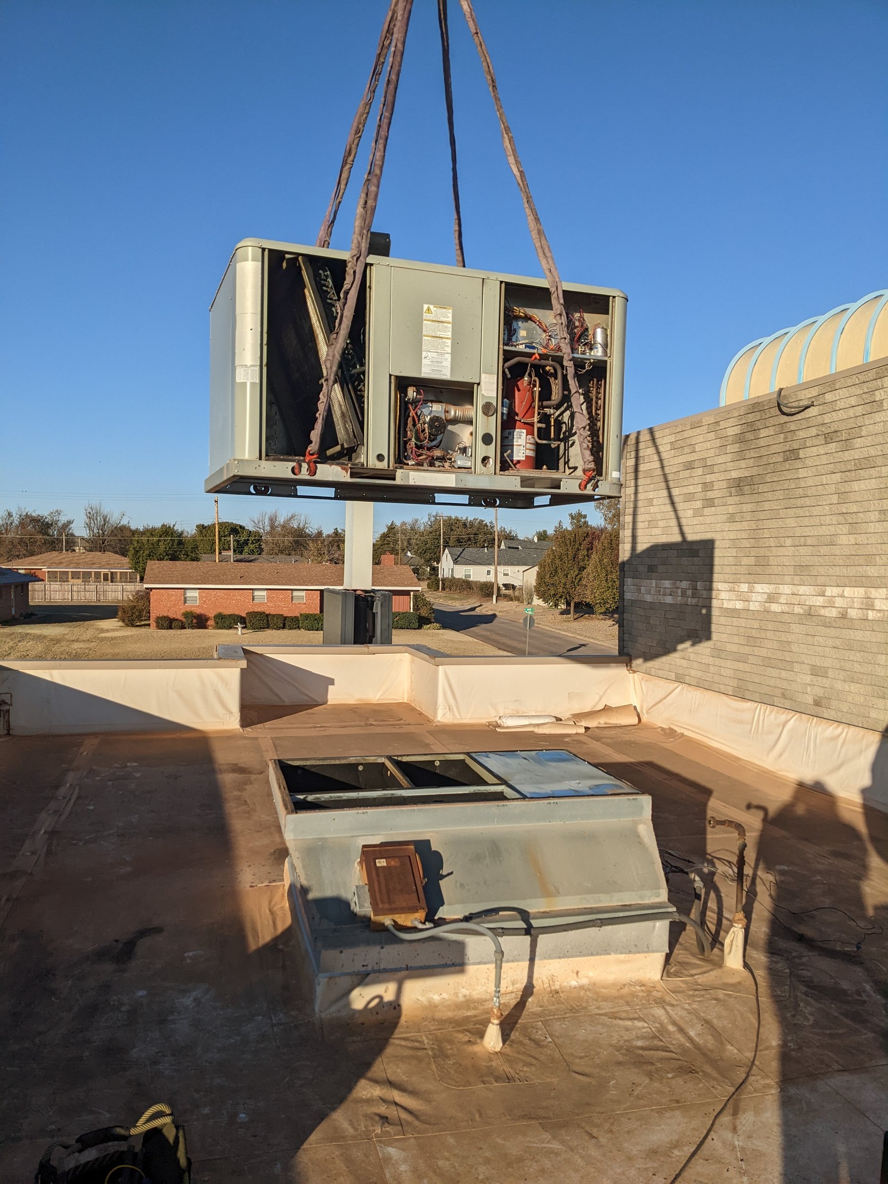Gas and electric packaged rooftop unit on a crane over the Sonic Drive-In roof in Kingfisher, Oklahoma during a Hartzell's Heat and Air rooftop replacement