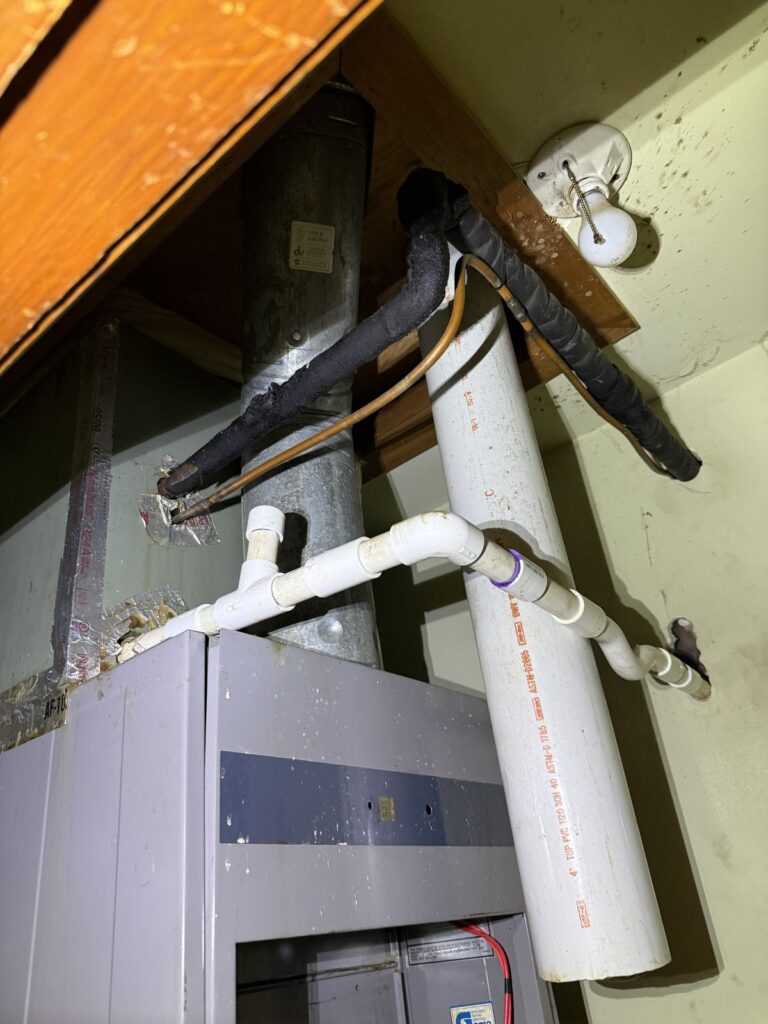 Furnace closet with refrigerant lines and PVC drain lines, a