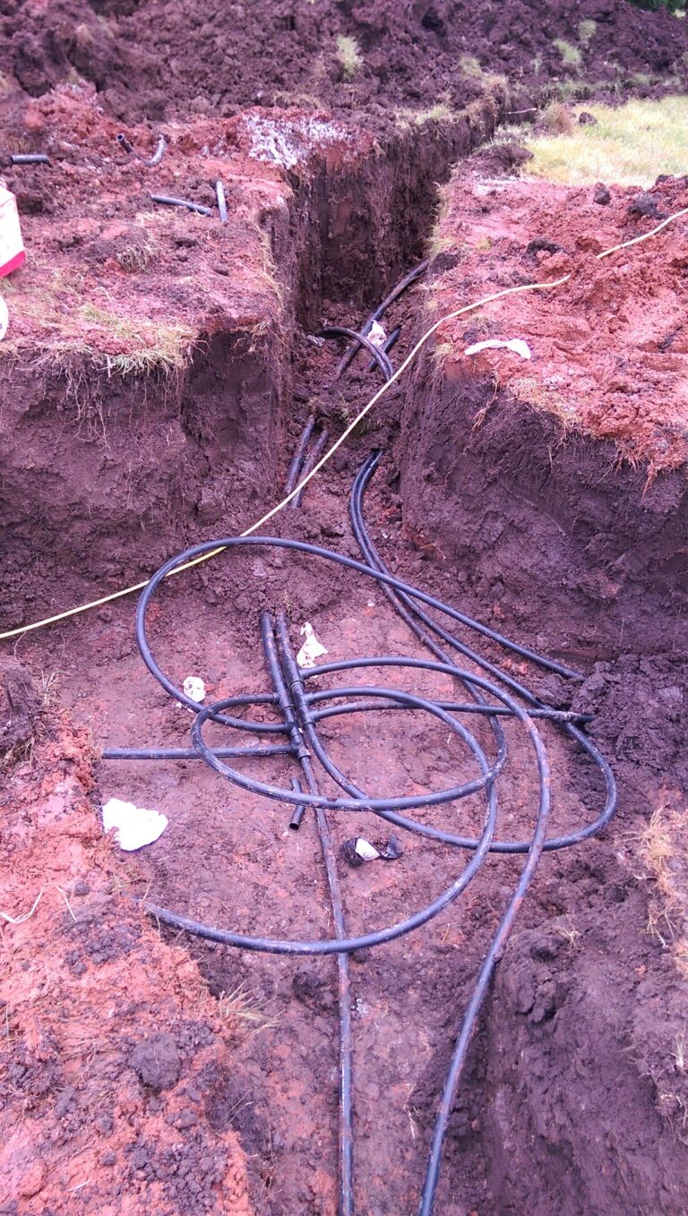 Open geothermal ground loop trench in red Oklahoma dirt before the slinky loop is laid in
