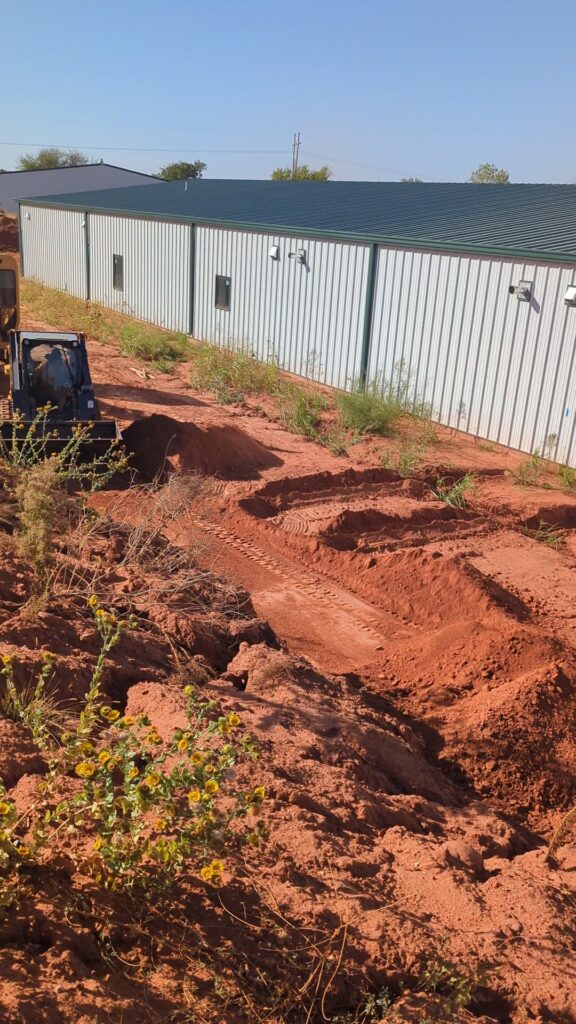 Several parallel geothermal slinky loop trenches cut in red Oklahoma dirt