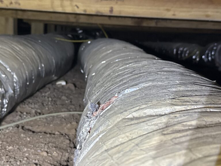 Old flex duct with its jacket torn open and the insulation exposed in a crawlspace in Okarche, Oklahoma