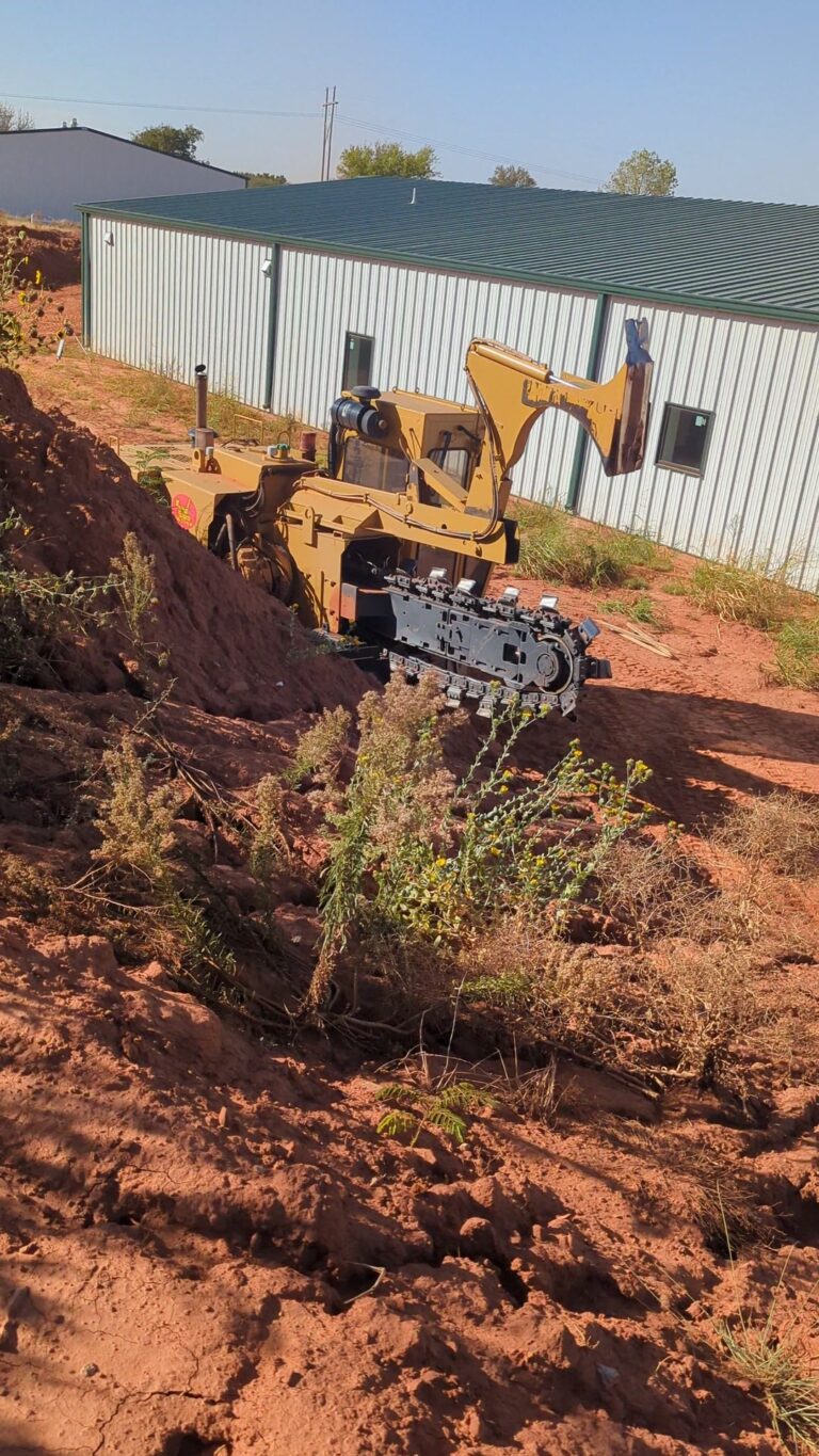 Chain trencher cutting a geothermal slinky loop trench through hard shale